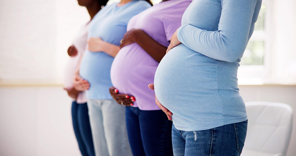 three pregnant women holding their bellies